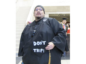 Student Holding mortar board with message: don't trip